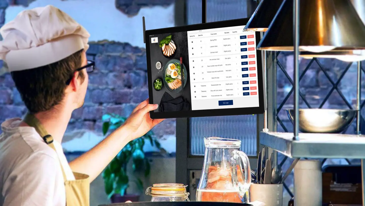 A chef in a kitchen looking at a list on a tablet