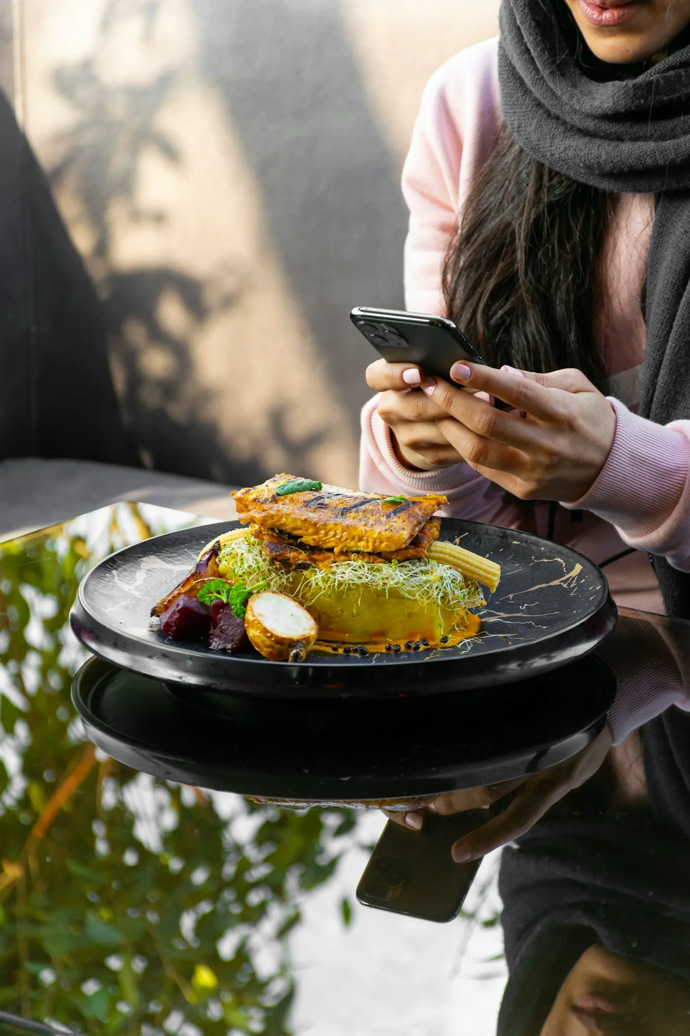 A person holding a phone beside a plate of food